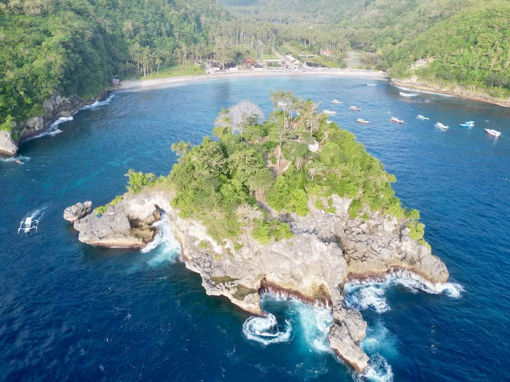 Pulau batu ikonik di Crystal Bay Nusa Penida dari drone dengan pantai dan garis pantai di latar belakang
