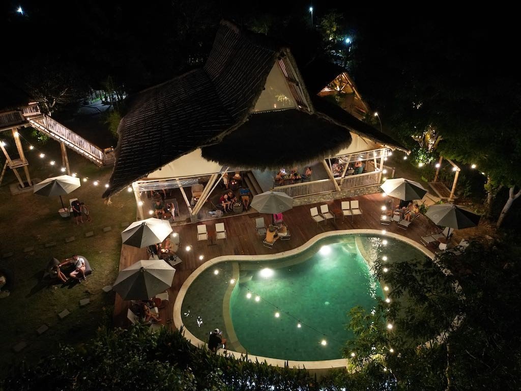 Sun Cliff Beat night at Amok — the illuminated infinity pool seen from a drone, Nusa Penida