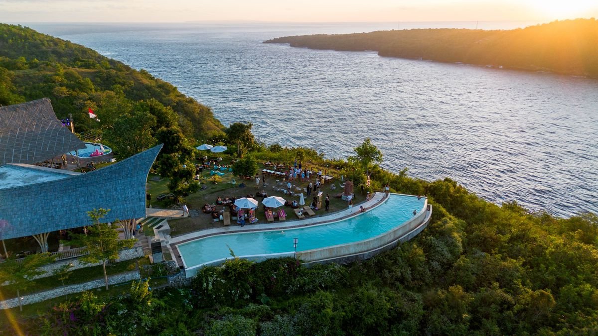 Amok Sun & Cliff Club's two infinity pools at golden hour, aerial drone view, Nusa Penida