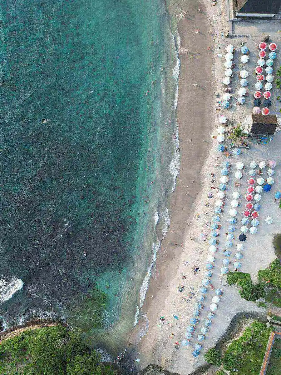 Aerial view of Crystal Bay Nusa Penida showing turquoise snorkeling water, the reef and sunbeds along the sand