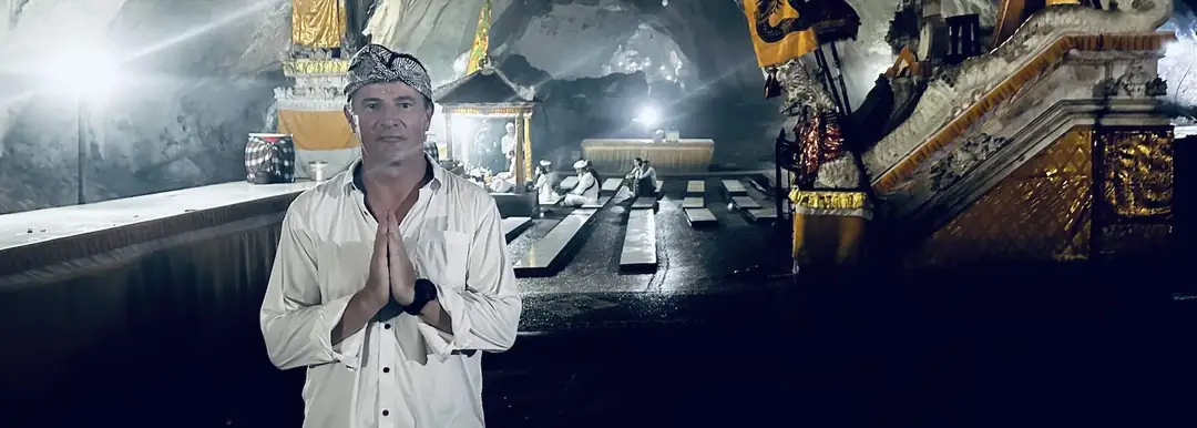 Blaise Jaeger in weißer balinesischer Tracht, die Hände zum Gebet gefaltet, im Höhlentempel Goa Giri Putri auf Nusa Penida