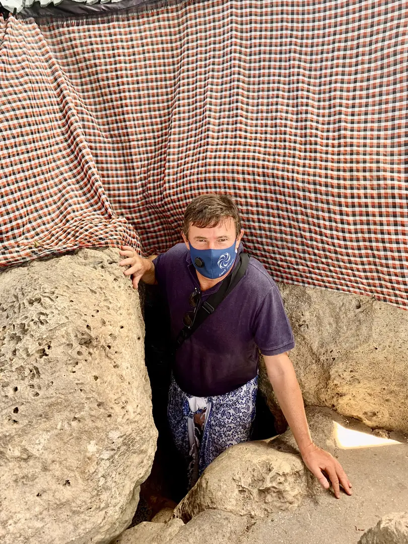 Besucher zwängt sich durch den engen Felsspalt, der den Eingang zum Höhlentempel Goa Giri Putri auf Nusa Penida bildet