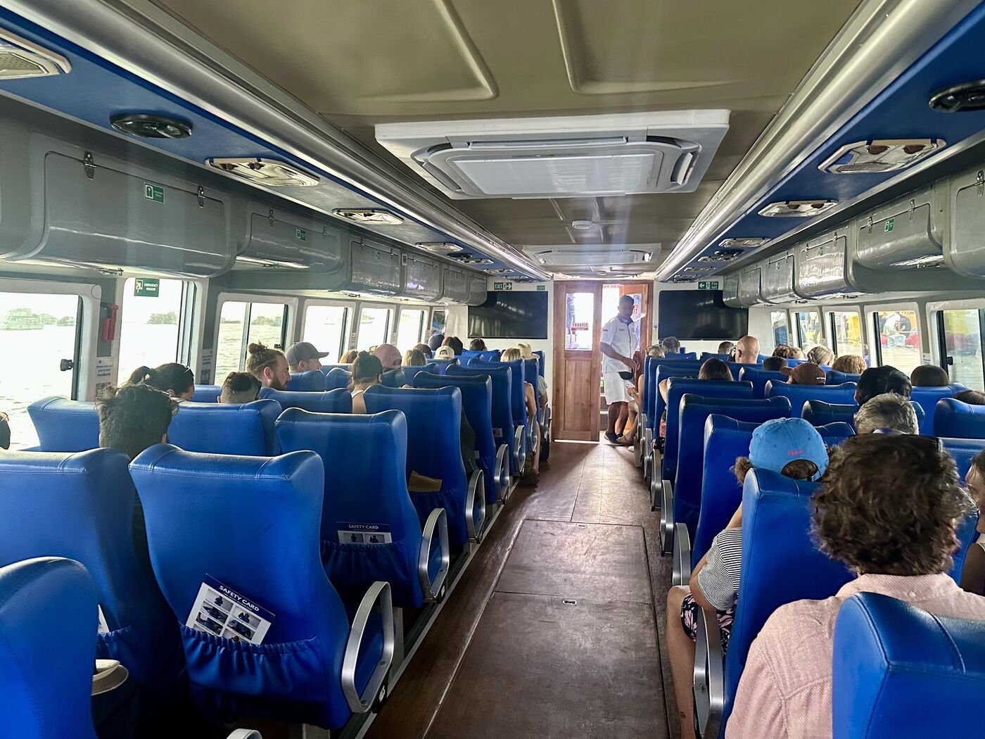 Inside a BlueWater Express fast boat with rows of seats and passengers on the crossing to the Gili Islands