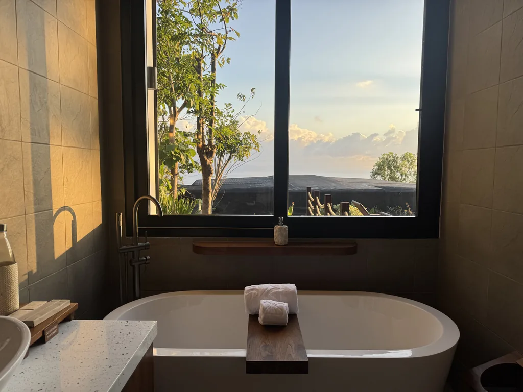 Bañera exenta junto a una ventana con vista al mar en la villa de un dormitorio de Adiwana Warnakali, Nusa Penida