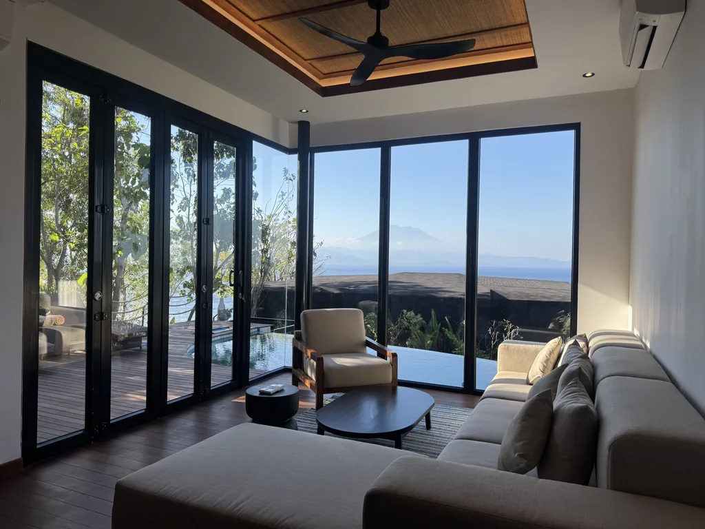 Salón de la villa de un dormitorio con piscina privada en Adiwana Warnakali, con techo de madera tallada y paredes de cristal a la terraza, Nusa Penida