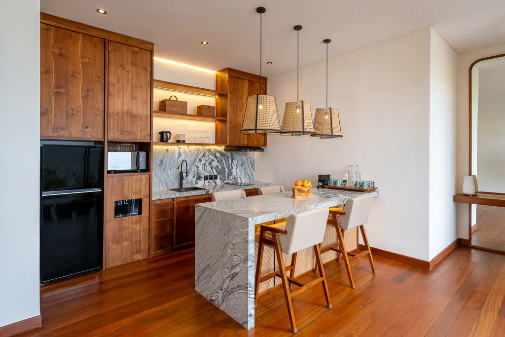 Cocina completa con isla de marmol y taburetes de bar en una villa con piscina privada de Adiwana Warnakali, Nusa Penida