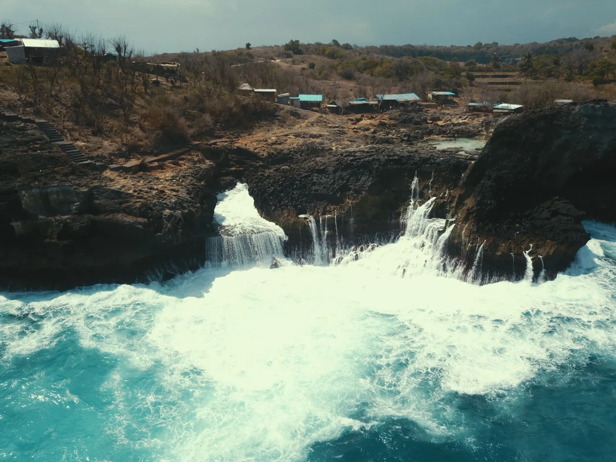A large wave flooding the Angel's Billabong natural rock pool with white water, Nusa Penida