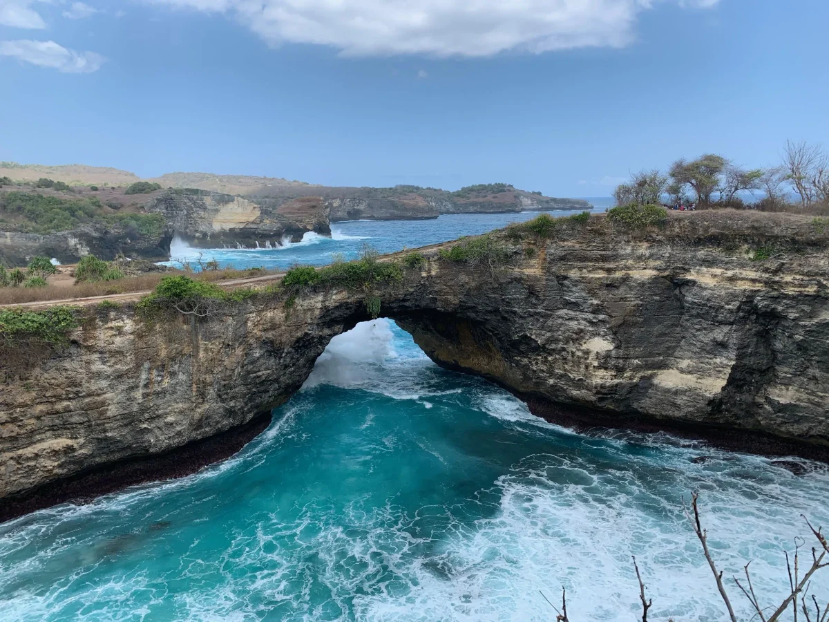 The Broken Beach arch seen from the clifftop with the bay full of white water, Nusa Penida