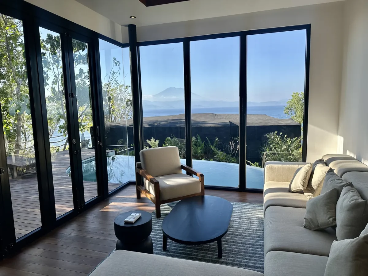 Living room of the 1-bedroom private-pool villa at Adiwana Warnakali, looking past the infinity pool to Mount Agung across the sea