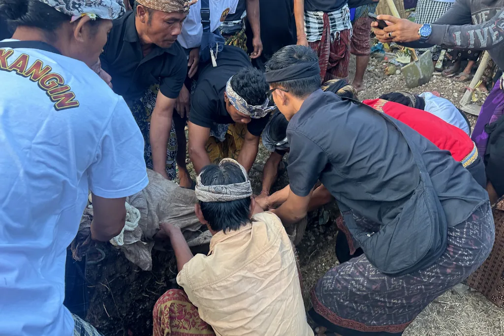 Family members carefully lifting the shrouded remains from a grave in Sebunibus