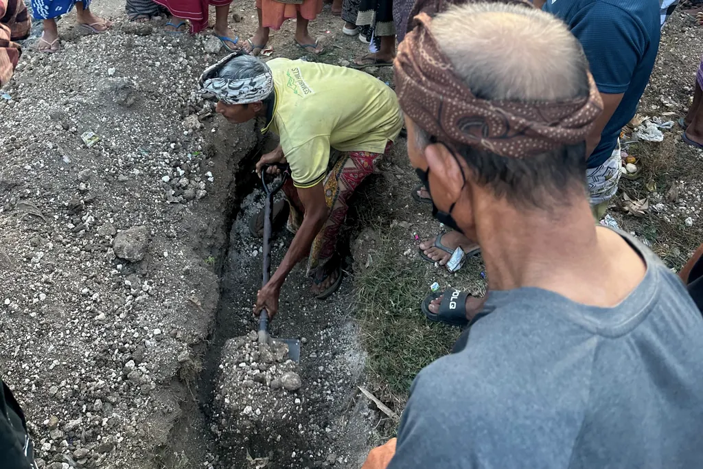 Family member digging a grave during the collective Ngaben ceremony in Sebunibus