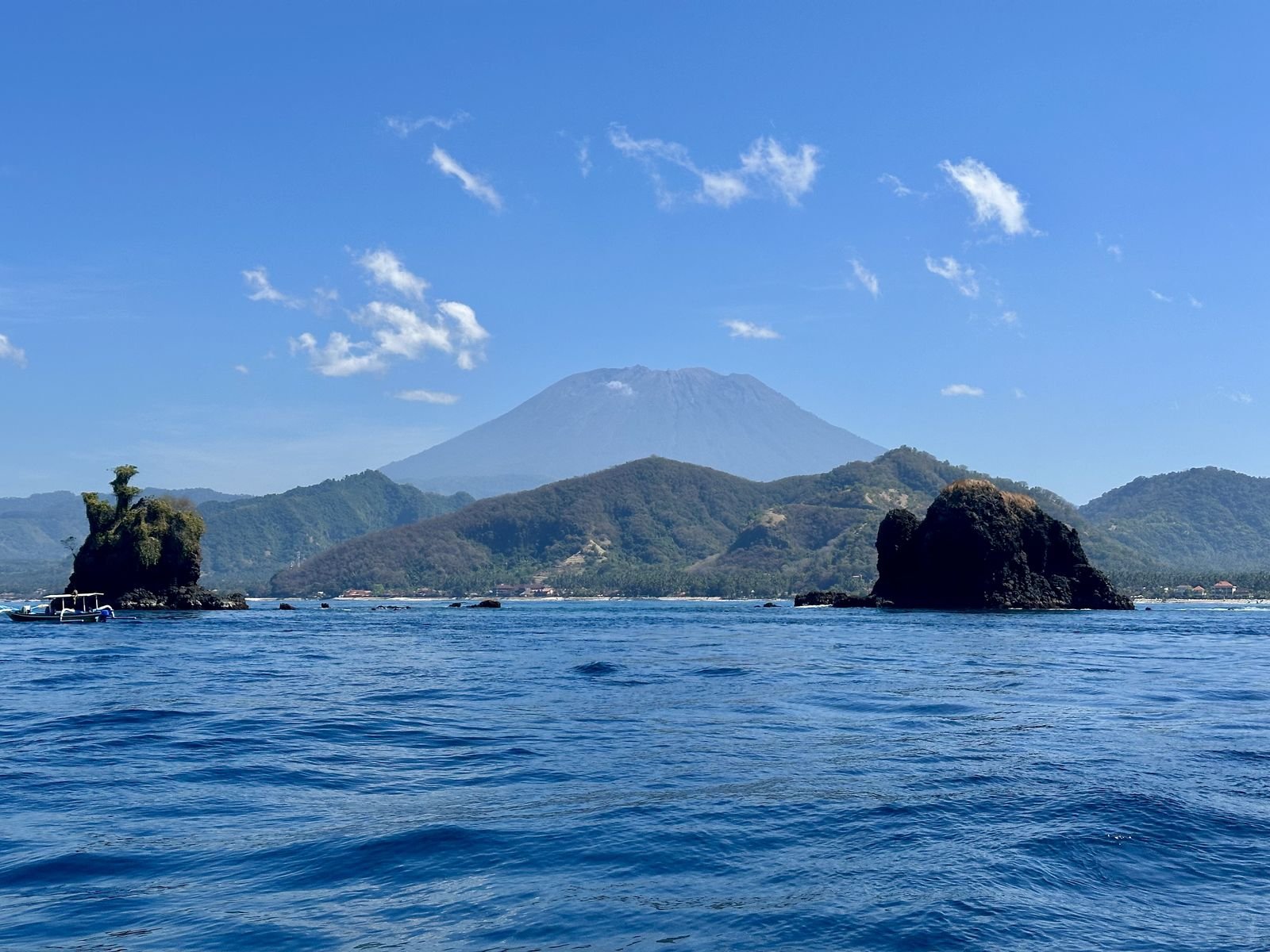 Die Felsen von Gili Mimpang im Vordergrund, dahinter Candidasa und am Horizont der Mount Agung, Bali